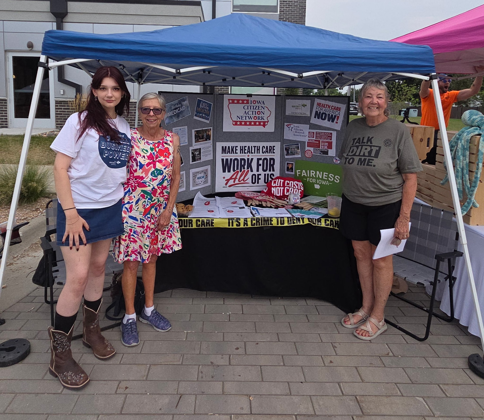 Volunteers at an Iowa Citizen Action Network table with campaign posters and handouts