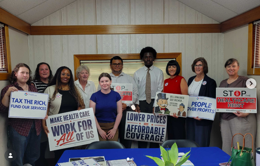 Advocates at a town hall holding Make Health Care Work for All of Us and Lower Prices, Affordable Coverage signs