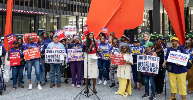 A speaker at a Chicago rally surrounded by advocates holding Medicaid Saves Lives signs